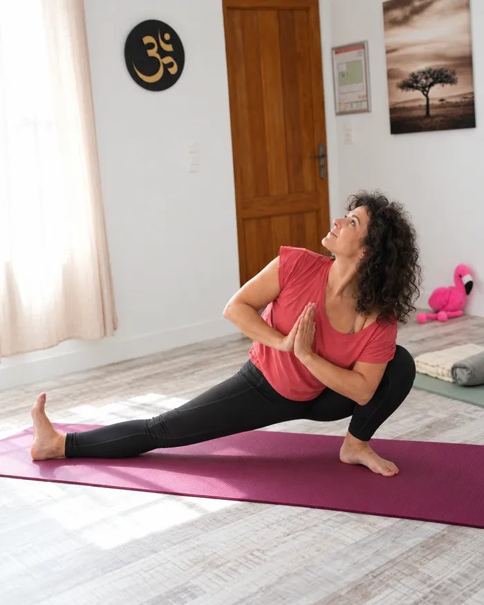 Alisson Bouquey en fente latérale, mains jointes et regard levé, sur son tapis de yoga