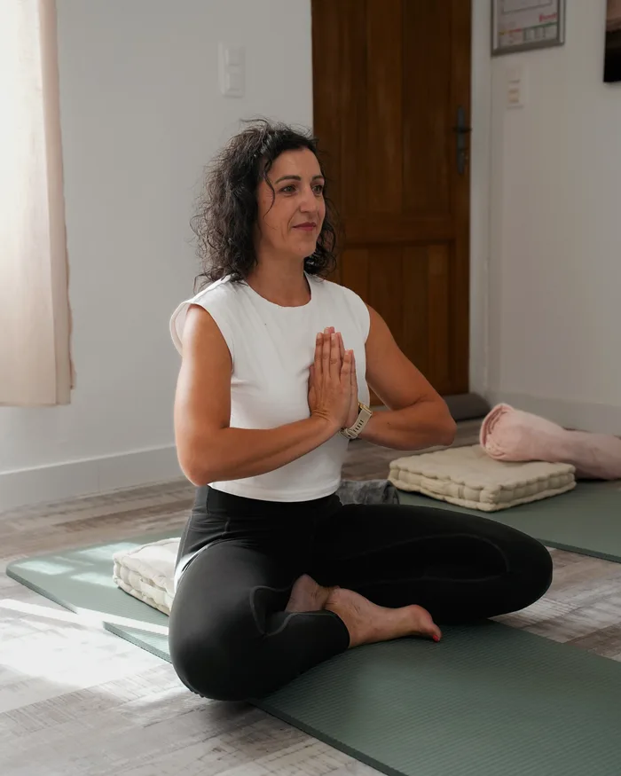 Laura Simon Phan, fondatrice du studio, assise en tailleur sur son tapis, mains jointes
