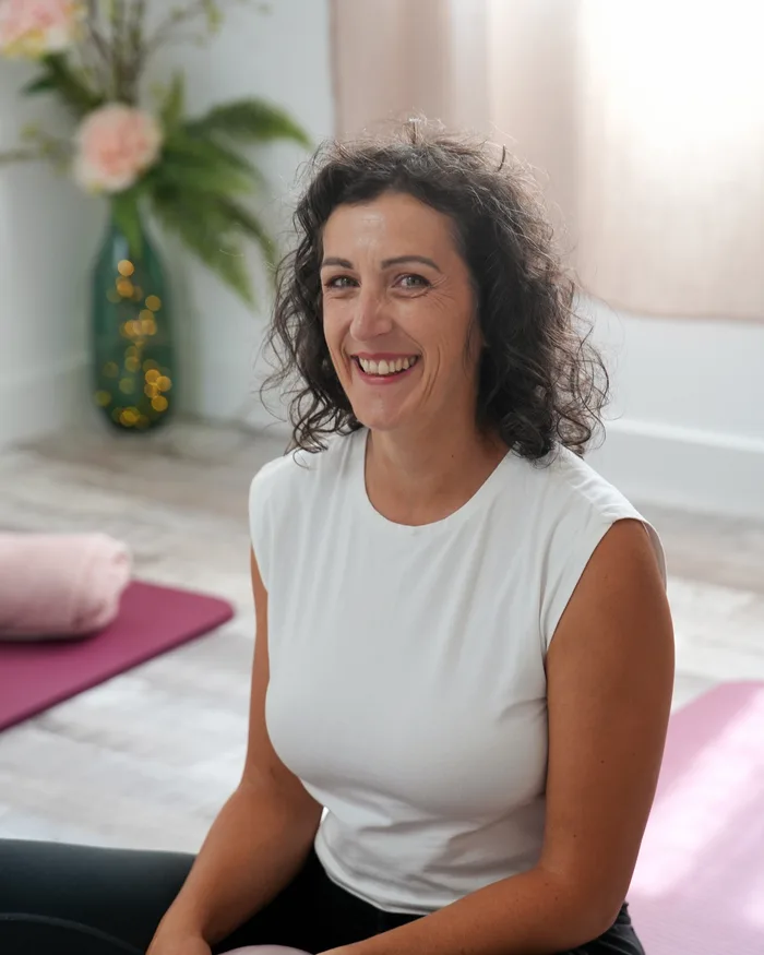 Laura Simon Phan souriante, assise sur un tapis dans la salle du studio à La Garde