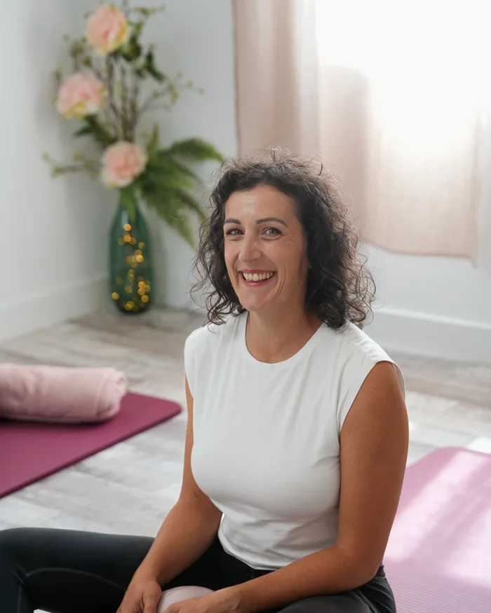 Laura assise sur un tapis avec un ballon de Pilates, dans la salle du studio à La Garde