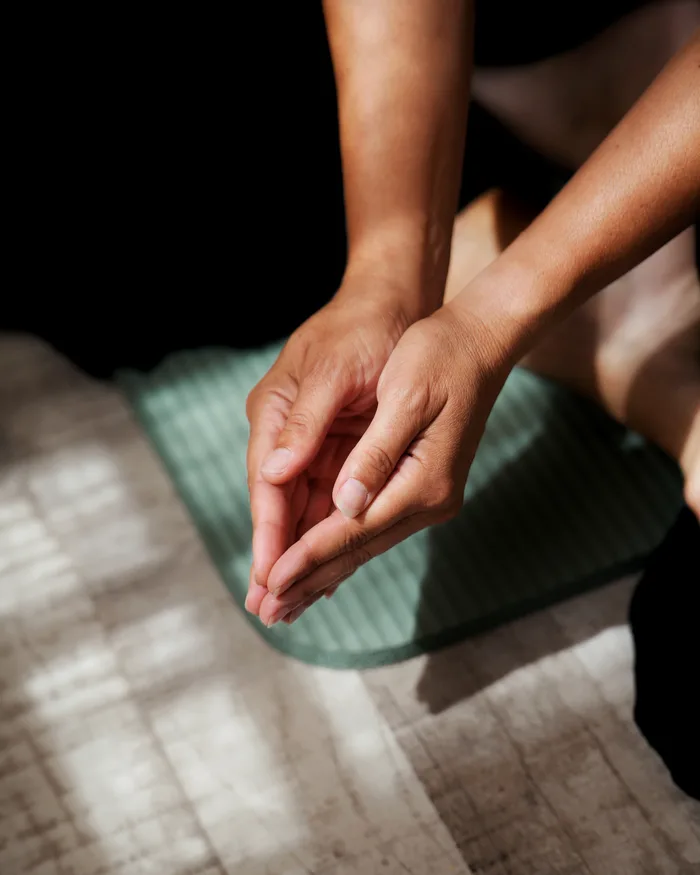 Mains ouvertes au-dessus d'un tapis, dans la lumière du matin, avant une séance de Reiki